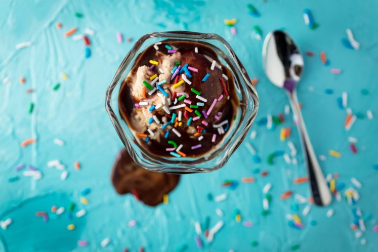 ice cream sundae with sprinkles blue background chocolate sauce