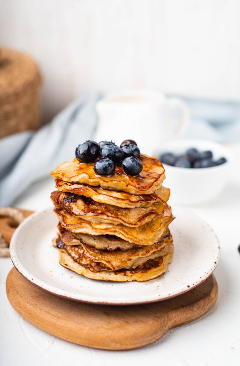 90 day meal plan banana pancakes stacked on a white plate topped with blueberries