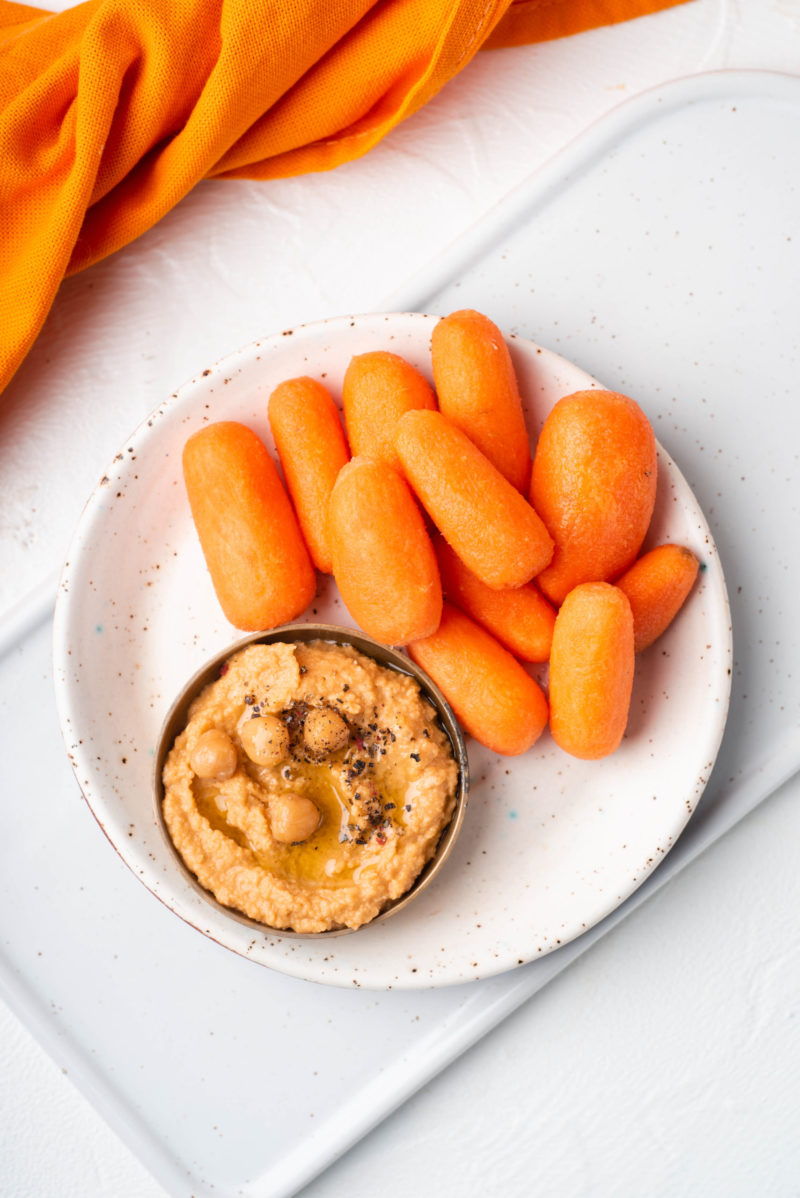 white plate with baby carrots and hummus blogilates snack 90 day journey