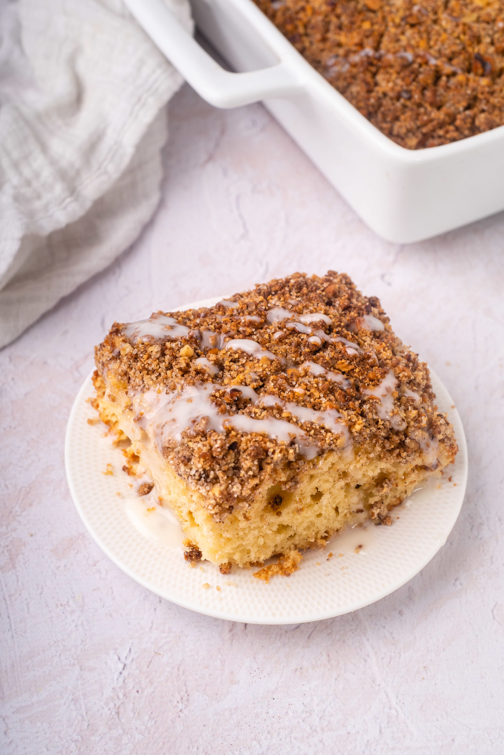 slice of gluten and dairy free cinnamon coffee cake with streusel and sugar free glaze on white plate
