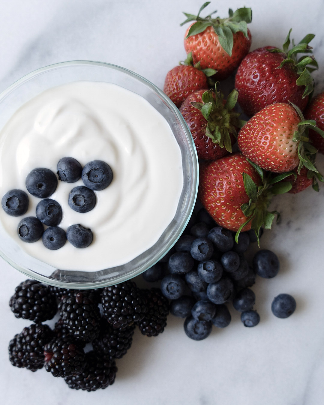 close up shot coconut fruit dip with strawberries and blueberries