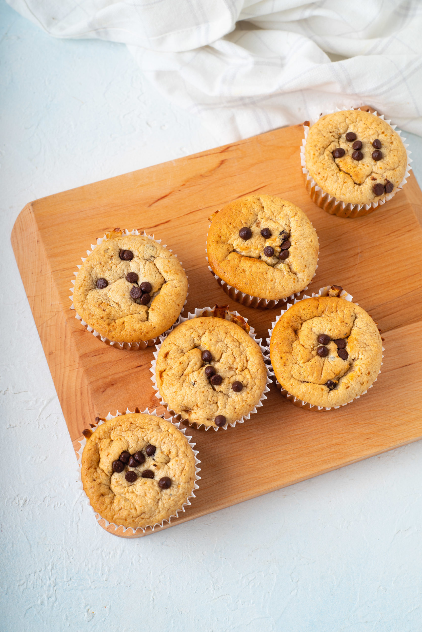 cutting board with batch of flourless blender muffins topped with chocolate chips blogilates