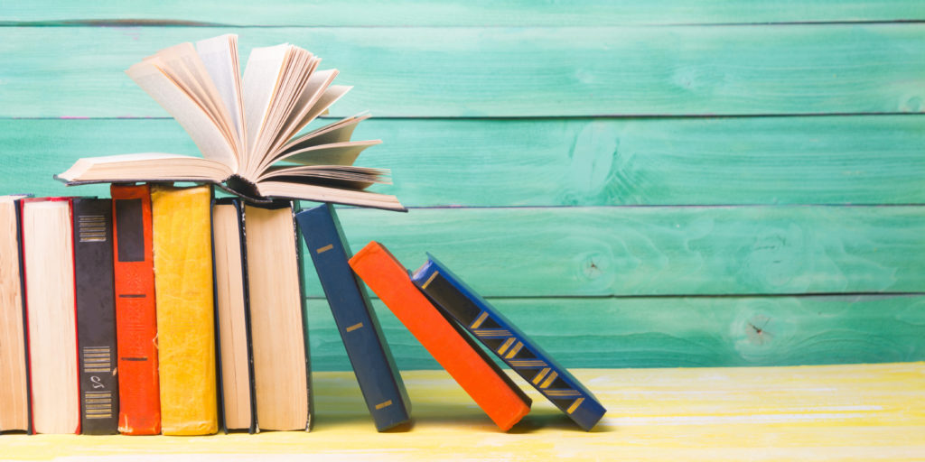 stack of books on a desk with wooden background