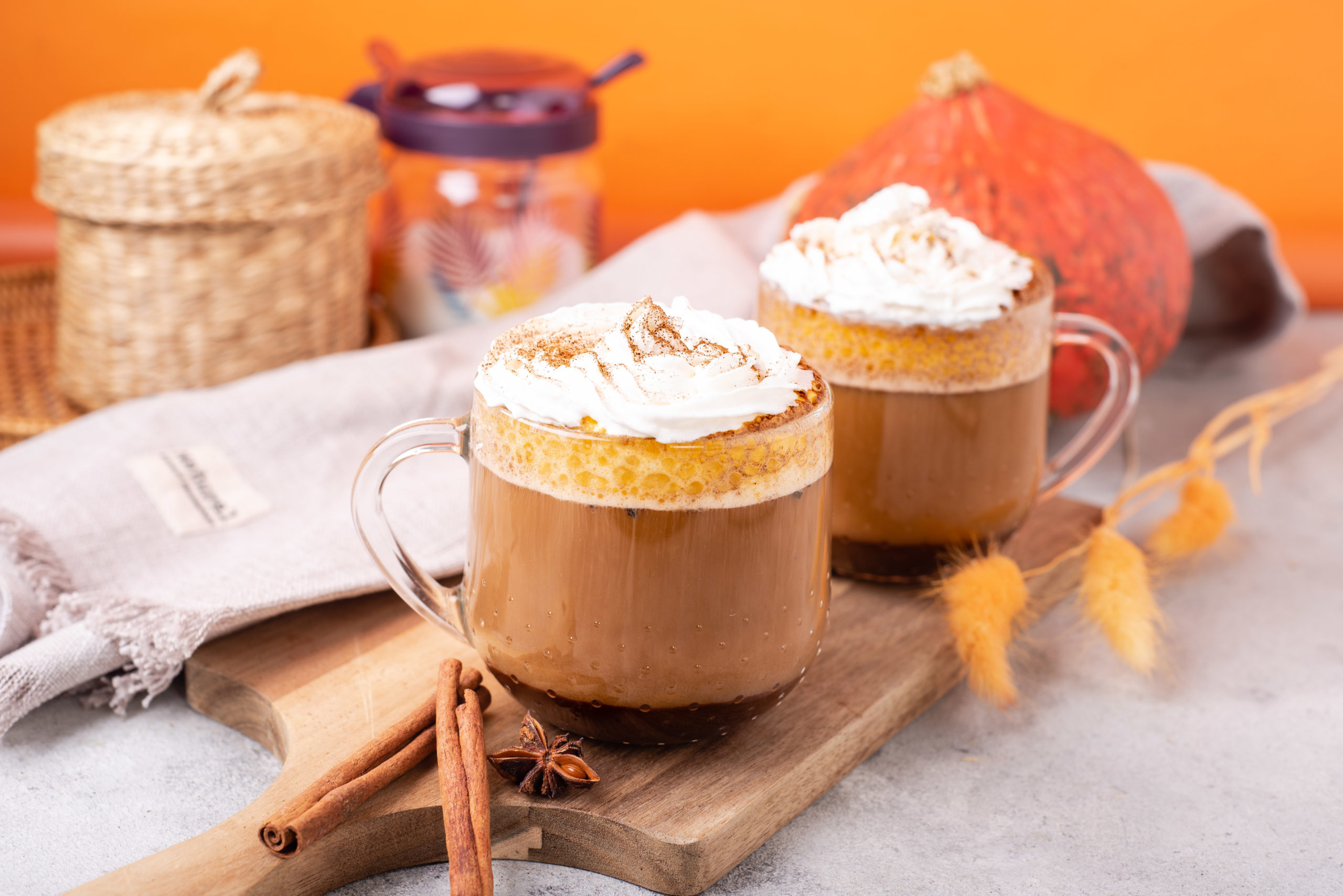 blogilates healthy pumpkin spice latte in clear mugs topped with coconut whipped cream side view with cinnamon sticks