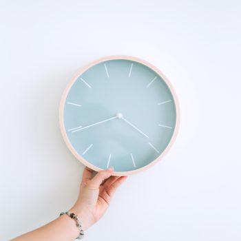 hand holding light blue clock on white background intermittent fasting and weight loss