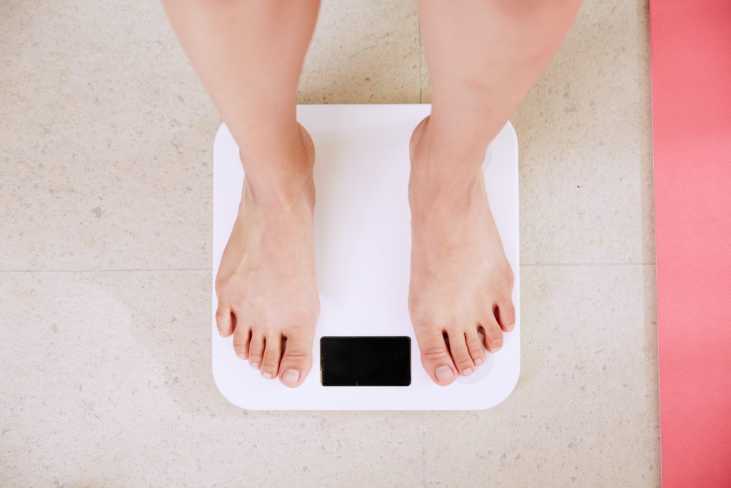 person standing on white scale importance of sleep in fitness and weight loss 