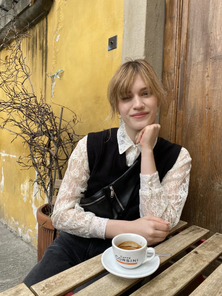 Kristen Kubek drinking coffee in Italy at cute outdoor table