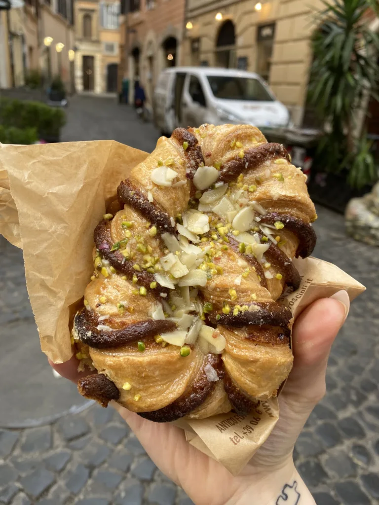 Hand holding Italian pastry on a cobblestone street in Italy