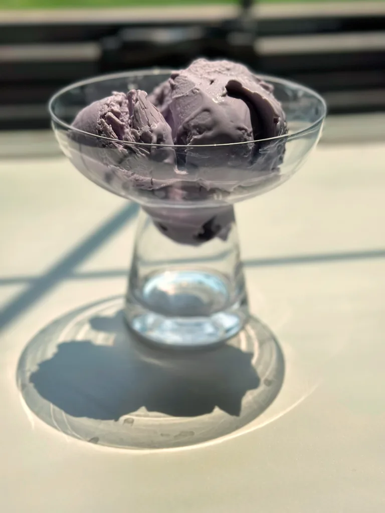 ninja creami ube ice cream made with blogilates sculpt + debloat ube soft serve and coconut milk in a glass dish sitting by a window