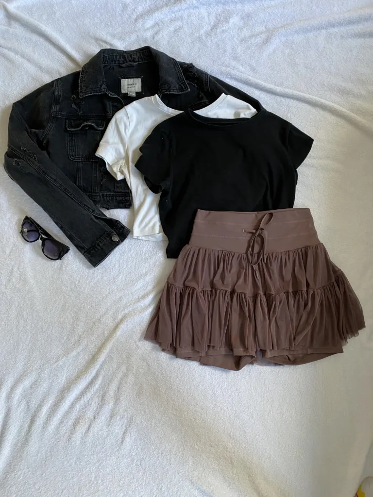 capsule wardrobe idea for travel black denim jacket basic tees and popflex pirouette skort with sunglasses