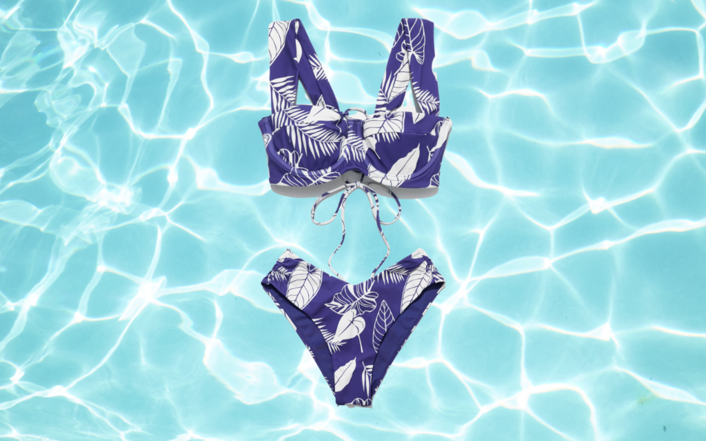 popflex boardwalk bombshell bikini top and low tide bottoms blue palm on a pool water background