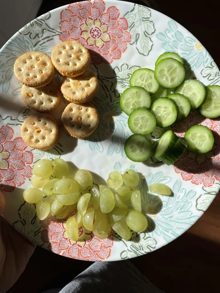 plate with cheese crackers, cucumber, and grapes